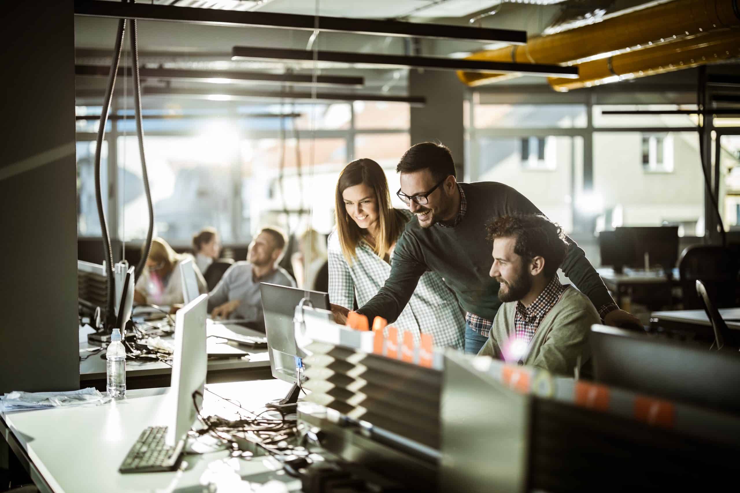 Group Of Happy Computer Programmers Working Together On Desktop Pc At